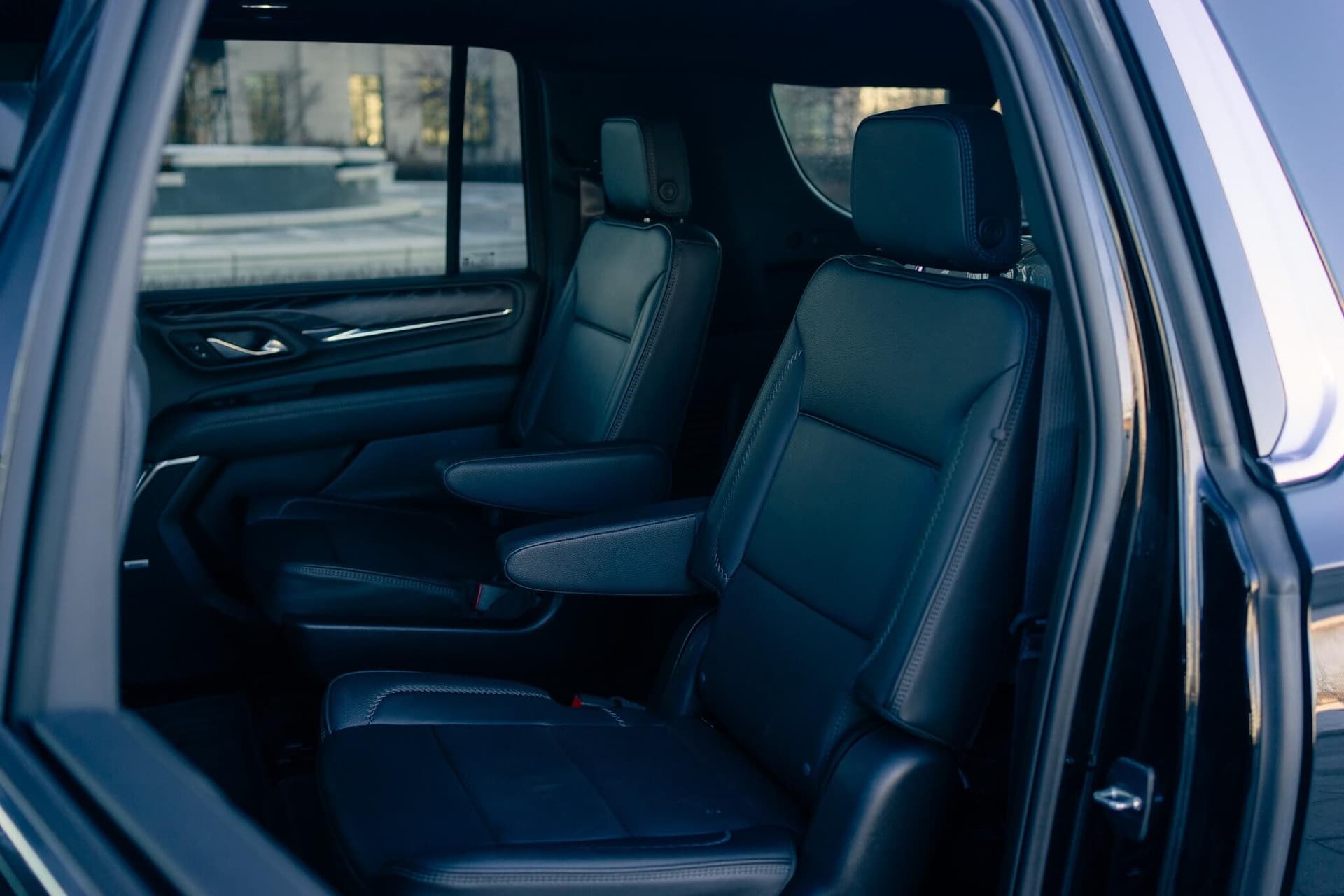 Black GMC Yukon XL on a dark reflective floor with golden edge light