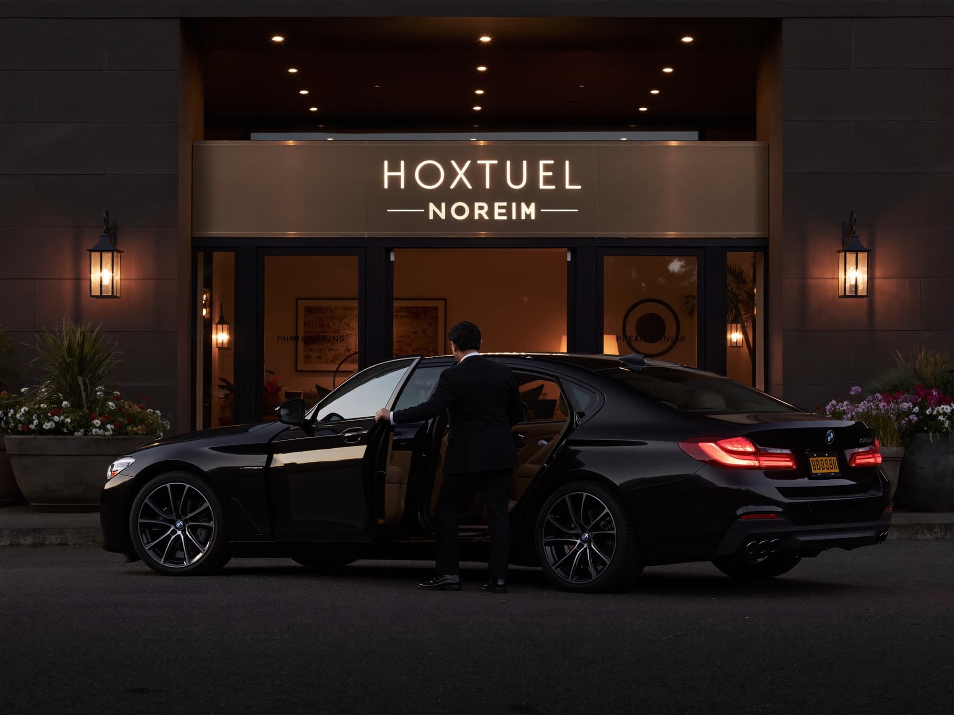 Chauffeur holding the door of a black sedan in front of a luxury hotel in Montreal